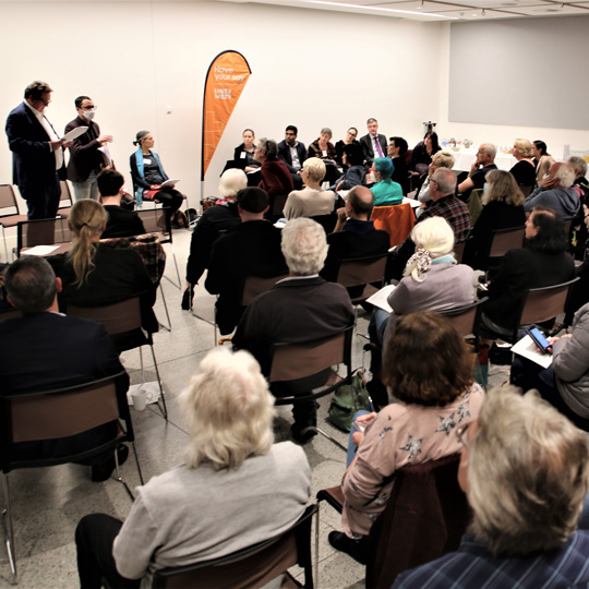 A group of people seated in a town-hall-style meeting